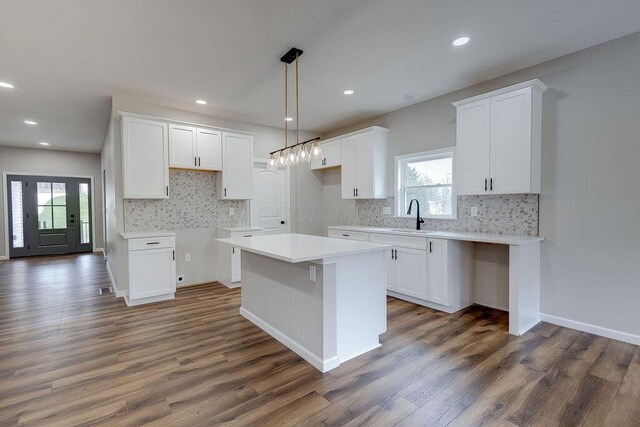 kitchen featuring a center island, dark wood-style flooring, a sink, and white cabinetry
