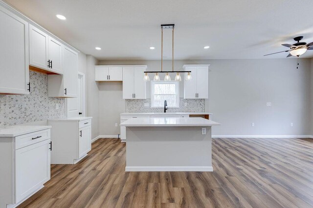 kitchen featuring wood finished floors, white cabinets, a ceiling fan, and a kitchen island