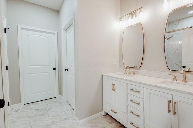 bathroom with double vanity, marble finish floor, a sink, and baseboards