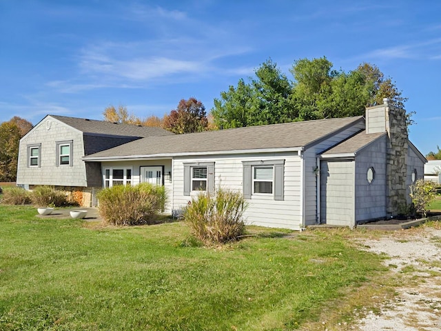 view of front of house featuring a front lawn, a chimney, and a shingled roof