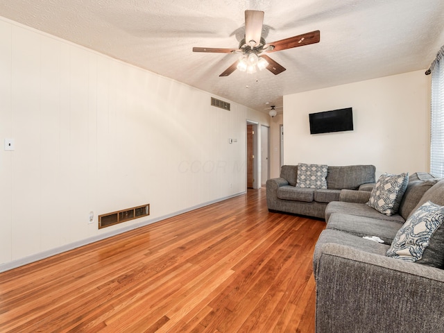 living room featuring hardwood / wood-style floors, a textured ceiling, and ceiling fan