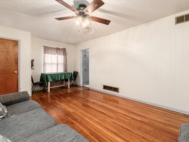 living room with dark hardwood / wood-style floors, ceiling fan, and a textured ceiling