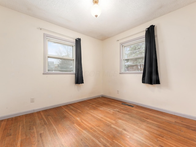 unfurnished room featuring a healthy amount of sunlight, wood-type flooring, and a textured ceiling