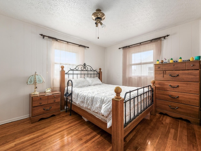 bedroom with a textured ceiling, ceiling fan, and dark wood-type flooring