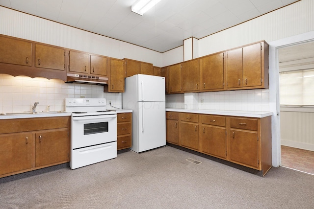 kitchen featuring decorative backsplash, white appliances, and light carpet