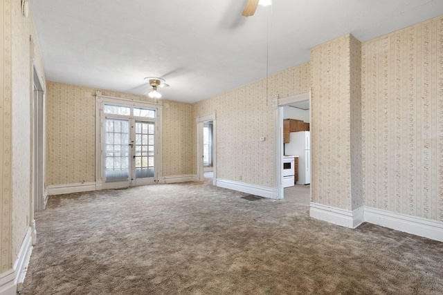 carpeted spare room with ceiling fan and french doors