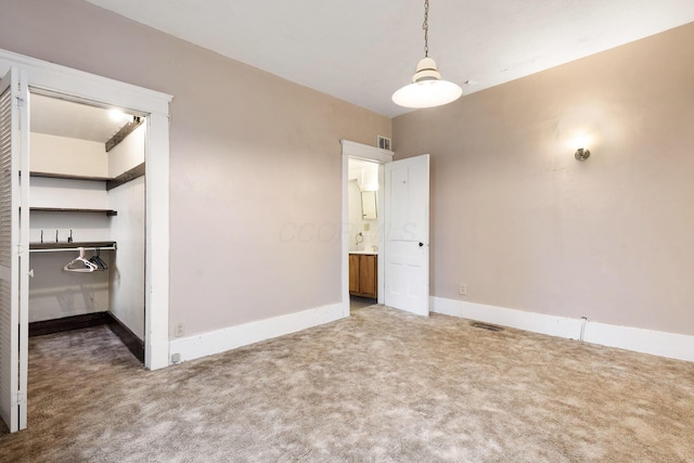 unfurnished bedroom featuring carpet, a walk in closet, and a closet