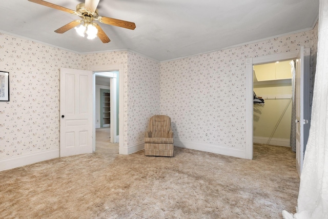 unfurnished bedroom with carpet flooring, ceiling fan, a walk in closet, and ornamental molding