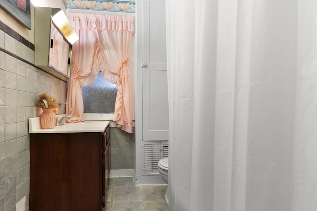 bathroom with toilet, vanity, tile patterned floors, and tile walls