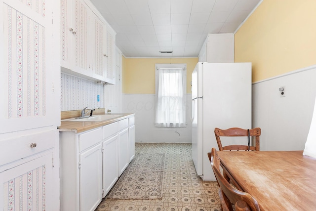 kitchen with white cabinets, white refrigerator, and sink