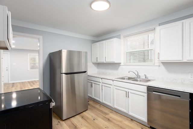 kitchen with white cabinetry, sink, stainless steel appliances, and light hardwood / wood-style floors