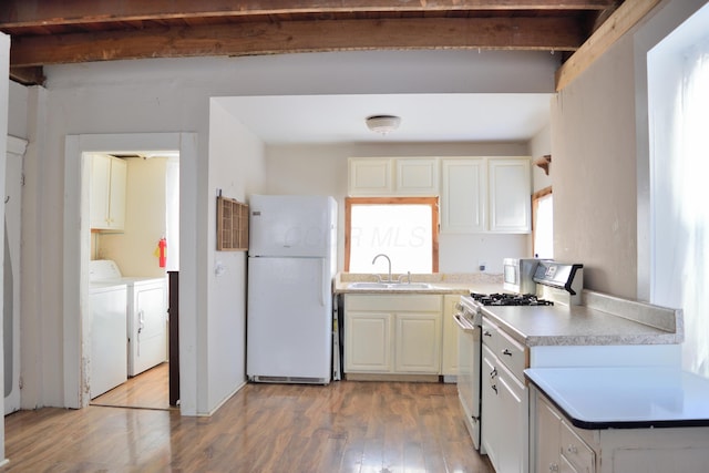 kitchen with sink, white appliances, washer and clothes dryer, hardwood / wood-style flooring, and white cabinets