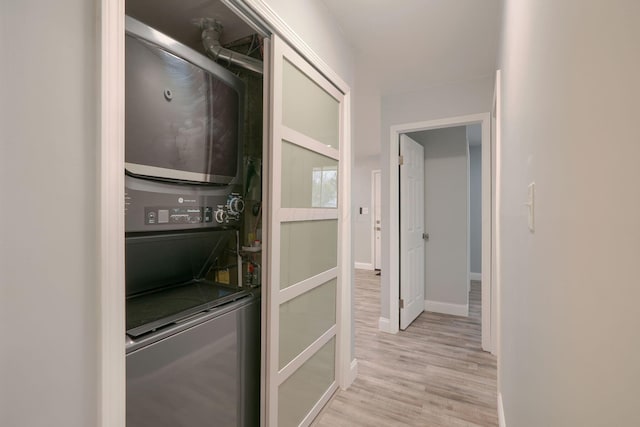 laundry area featuring stacked washer and dryer and light hardwood / wood-style flooring