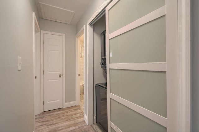 hall featuring light wood-type flooring and stacked washer and dryer