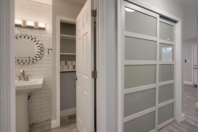 bathroom with sink, wood-type flooring, and tile walls