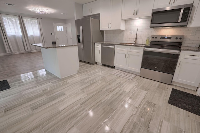 kitchen with dark stone countertops, white cabinetry, sink, and appliances with stainless steel finishes