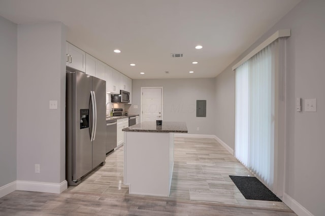 kitchen featuring a center island, white cabinets, dark stone countertops, light wood-type flooring, and appliances with stainless steel finishes