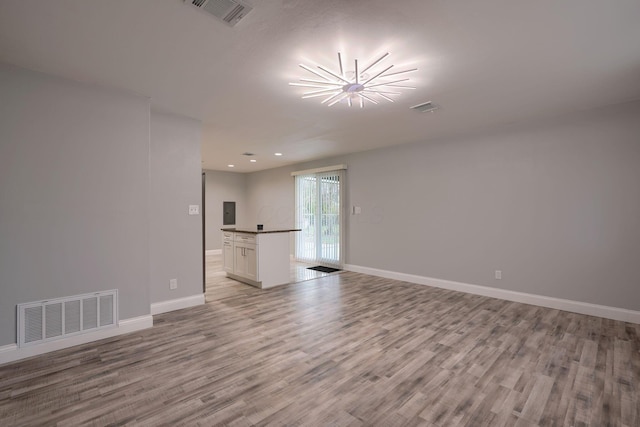 unfurnished living room with light wood-type flooring and a chandelier