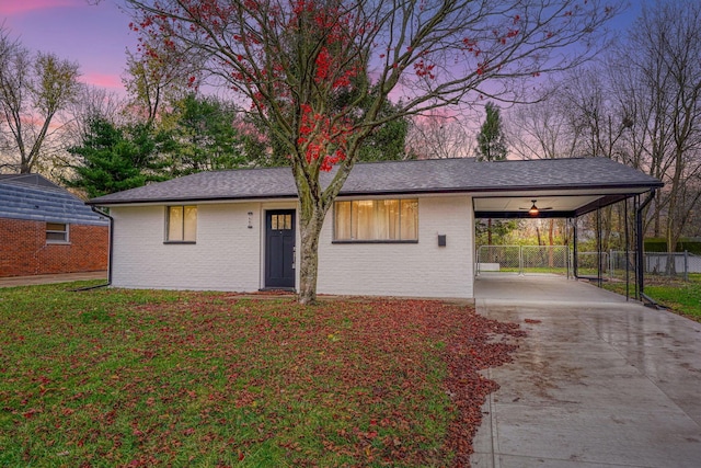 ranch-style home featuring ceiling fan, a yard, and a carport