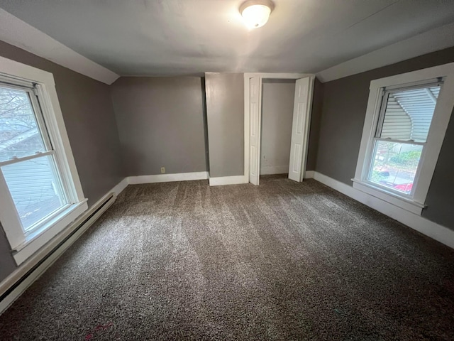 unfurnished bedroom with carpet, lofted ceiling, multiple windows, and a baseboard heating unit