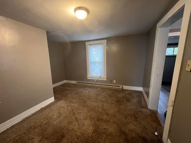 empty room featuring dark colored carpet and baseboard heating