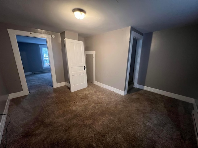 unfurnished bedroom featuring dark colored carpet and baseboard heating