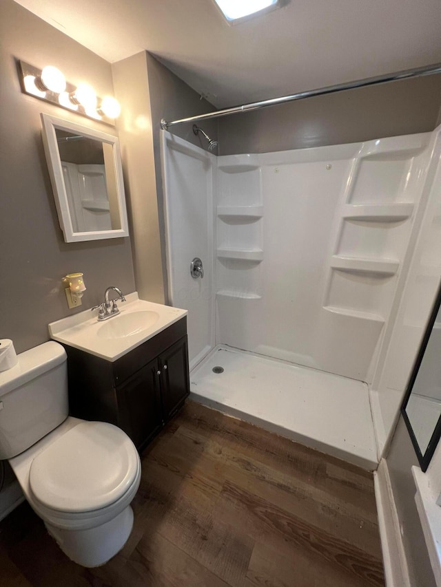 bathroom with vanity, toilet, wood-type flooring, and walk in shower