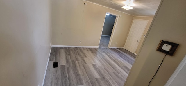 unfurnished room featuring crown molding and light wood-type flooring