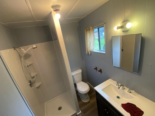 bathroom featuring wood-type flooring, vanity, toilet, and walk in shower