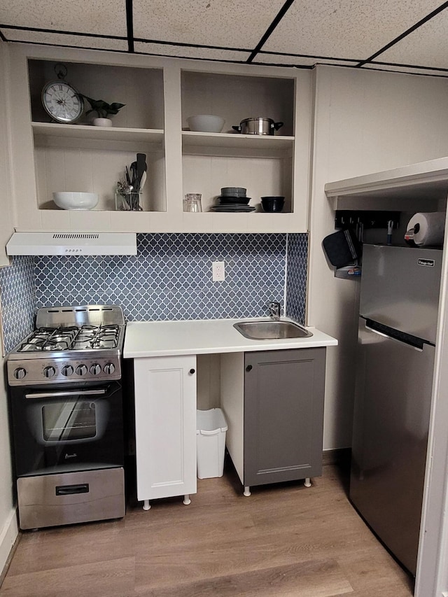 kitchen with a paneled ceiling, exhaust hood, sink, appliances with stainless steel finishes, and light hardwood / wood-style floors