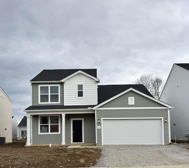 traditional-style home with an attached garage, gravel driveway, and central air condition unit