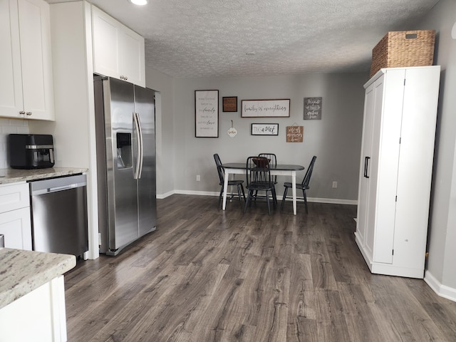 kitchen with a textured ceiling, stainless steel appliances, white cabinetry, and dark wood-type flooring