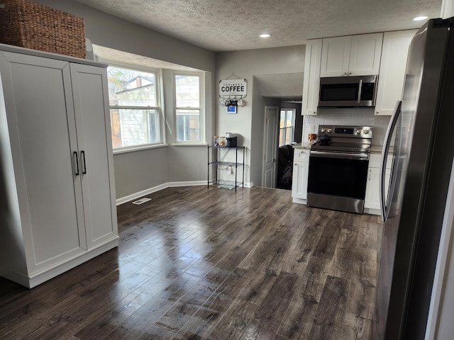 kitchen with backsplash, white cabinets, dark hardwood / wood-style floors, a textured ceiling, and appliances with stainless steel finishes