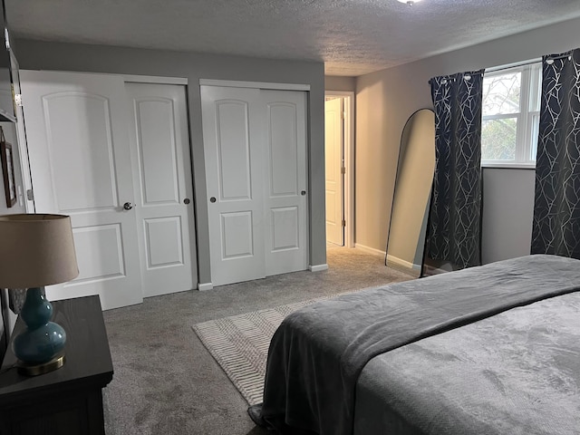 carpeted bedroom with a textured ceiling and two closets