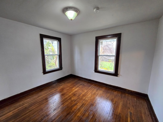 spare room with a wealth of natural light and dark wood-type flooring