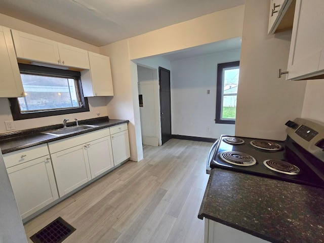 kitchen featuring light wood-type flooring, electric stove, white cabinetry, and sink