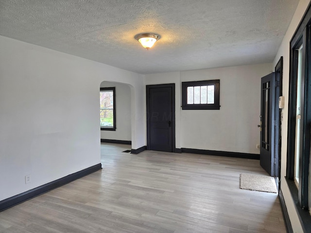 empty room with light hardwood / wood-style flooring and a textured ceiling