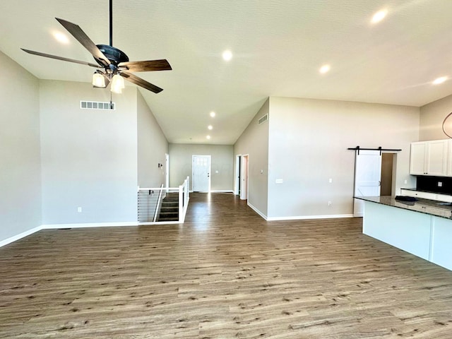 unfurnished living room with a barn door, light hardwood / wood-style flooring, and ceiling fan