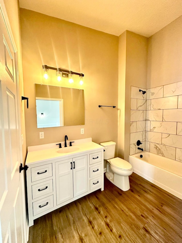 full bathroom featuring hardwood / wood-style flooring, tiled shower / bath combo, toilet, and vanity