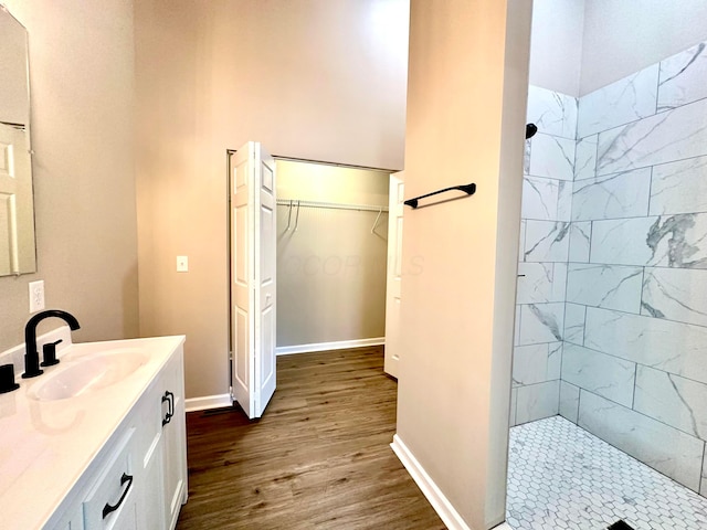 bathroom with tiled shower, wood-type flooring, and vanity