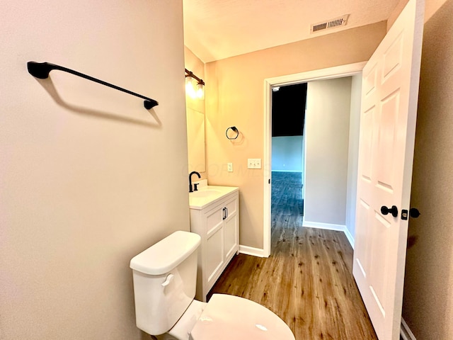 bathroom with hardwood / wood-style floors, vanity, and toilet