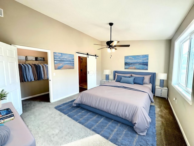 bedroom featuring dark carpet, ceiling fan, a barn door, a closet, and lofted ceiling