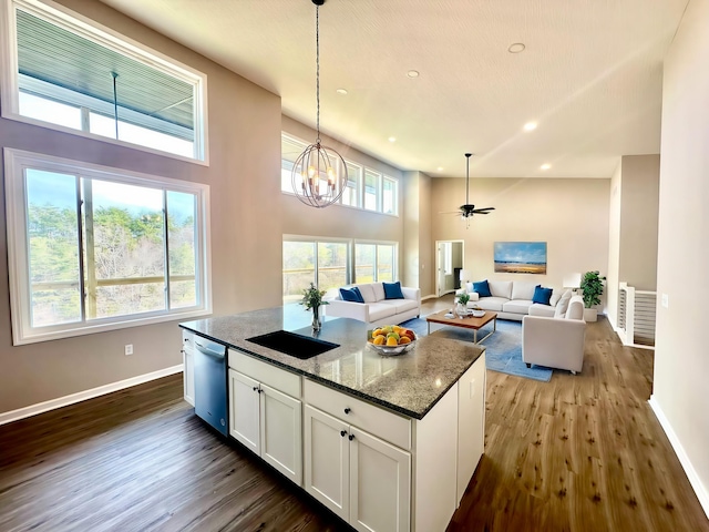 kitchen with stainless steel dishwasher, high vaulted ceiling, white cabinetry, and dark stone counters