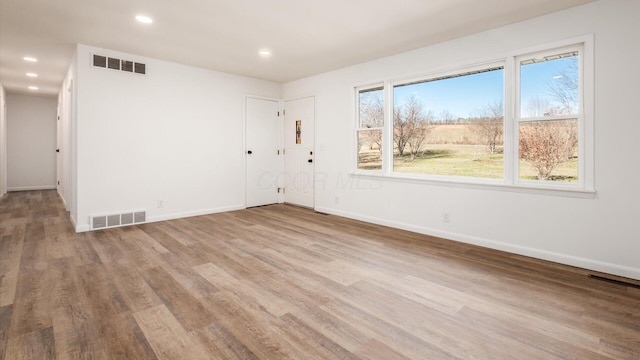 unfurnished room with a healthy amount of sunlight and light hardwood / wood-style floors