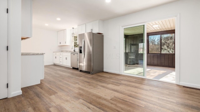 kitchen with white cabinets, stainless steel refrigerator with ice dispenser, white dishwasher, and light hardwood / wood-style floors