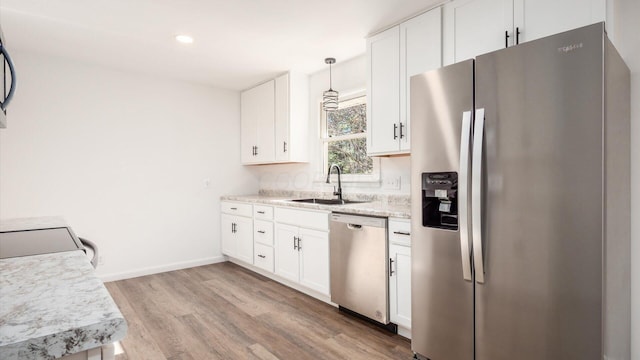 kitchen featuring appliances with stainless steel finishes, white cabinetry, hanging light fixtures, and sink