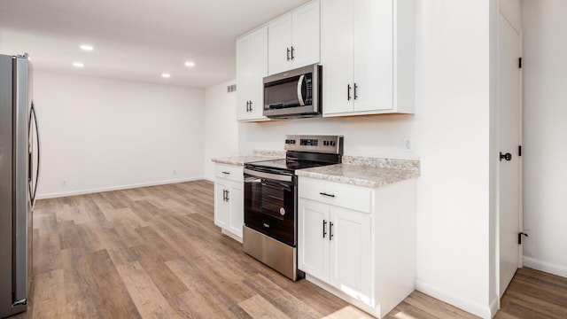 kitchen with white cabinetry, light stone counters, light wood-type flooring, and stainless steel appliances