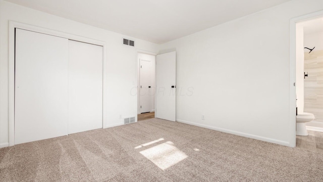 unfurnished bedroom with connected bathroom, a closet, and carpet