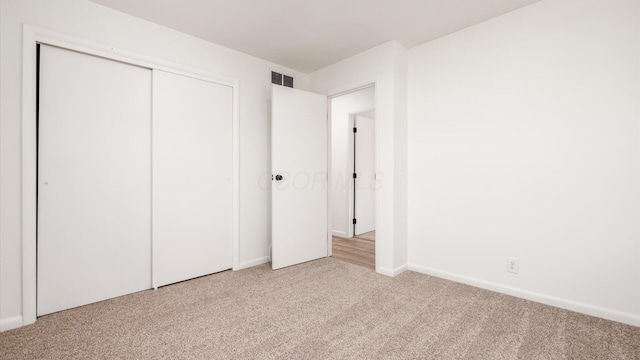 unfurnished bedroom with light carpet and a closet