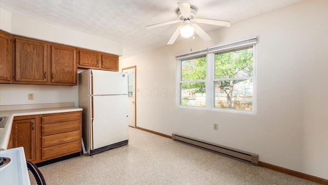 kitchen featuring a textured ceiling, baseboard heating, ceiling fan, range, and white fridge